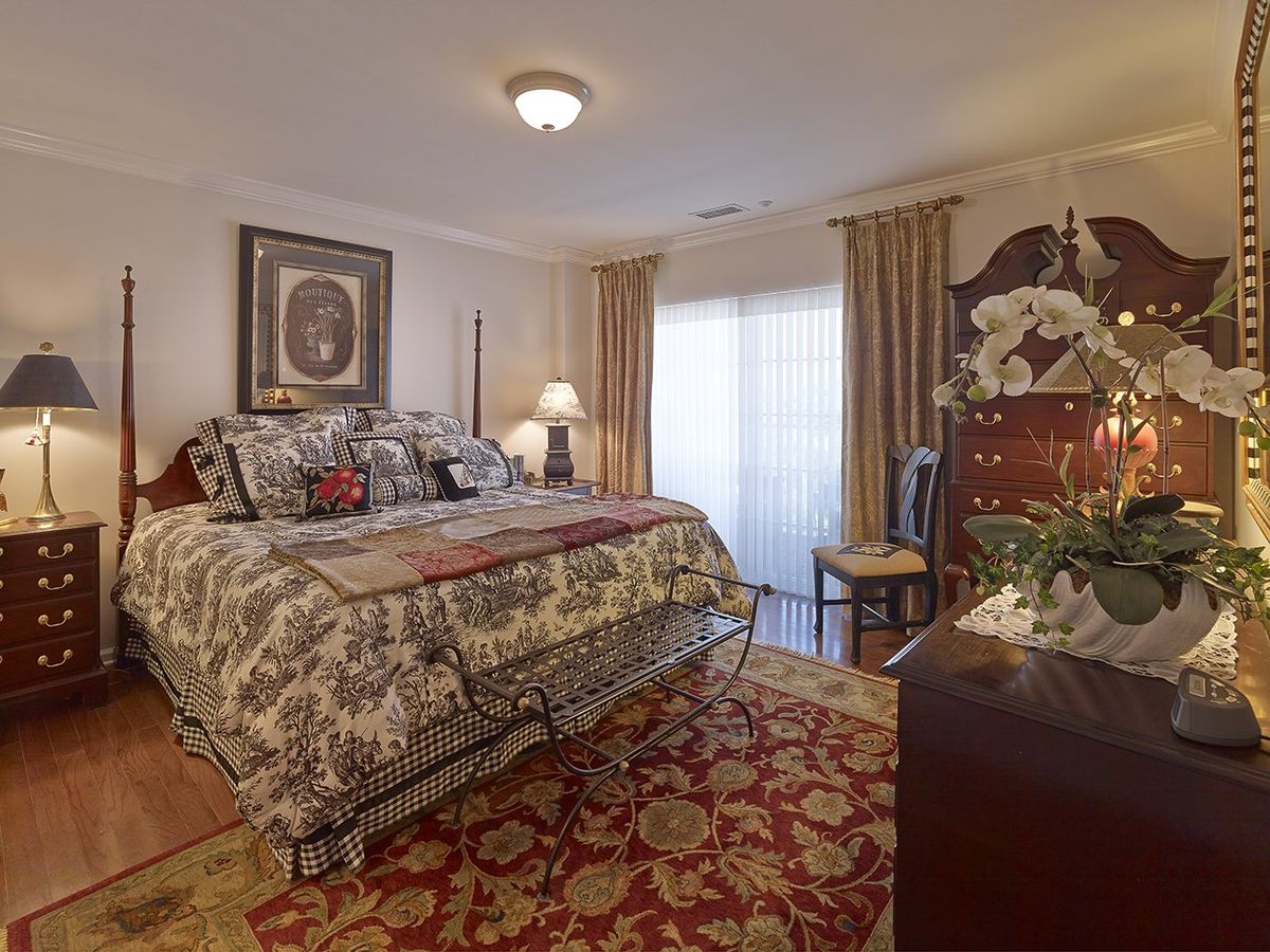 A traditionally decorated bedroom with a large bed, patterned rug, and elegant curtains.