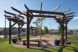 A sunny outdoor park with a wooden pergola and benches.