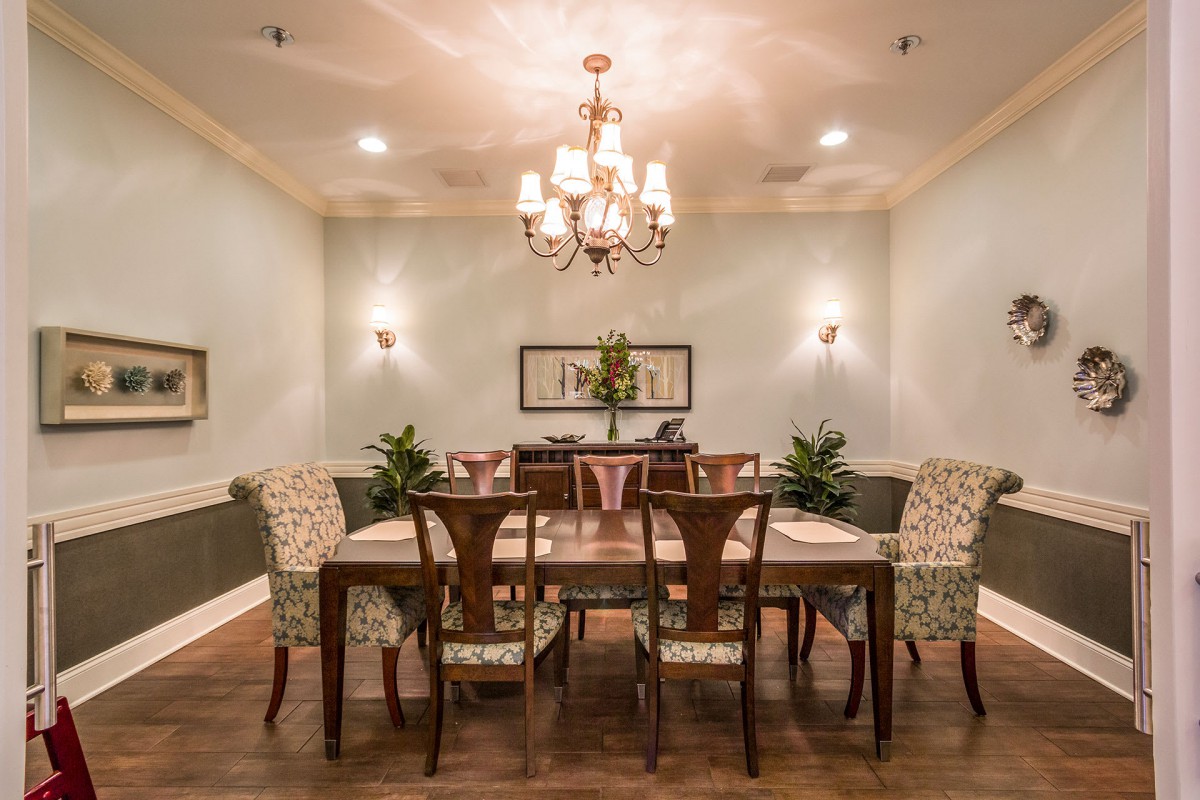 A beautifully decorated dining room with a large table, elegant chairs, and a chandelier providing ambient lighting.