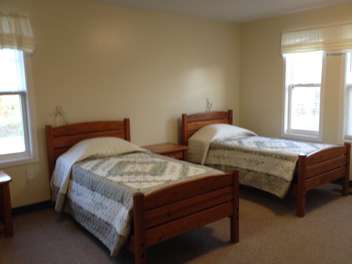 A simple bedroom with two twin beds and a window.