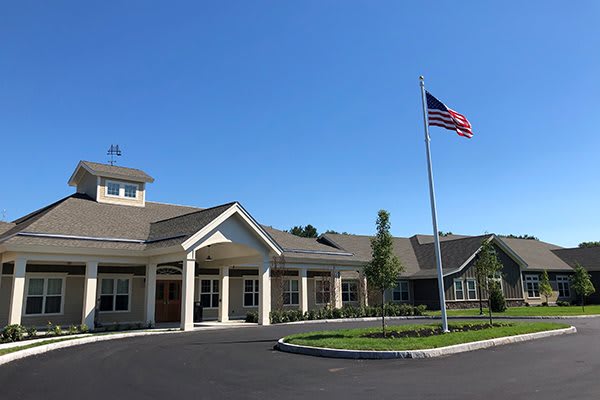 An exterior view of a building with an American flag in front, set against a clear blue sky.