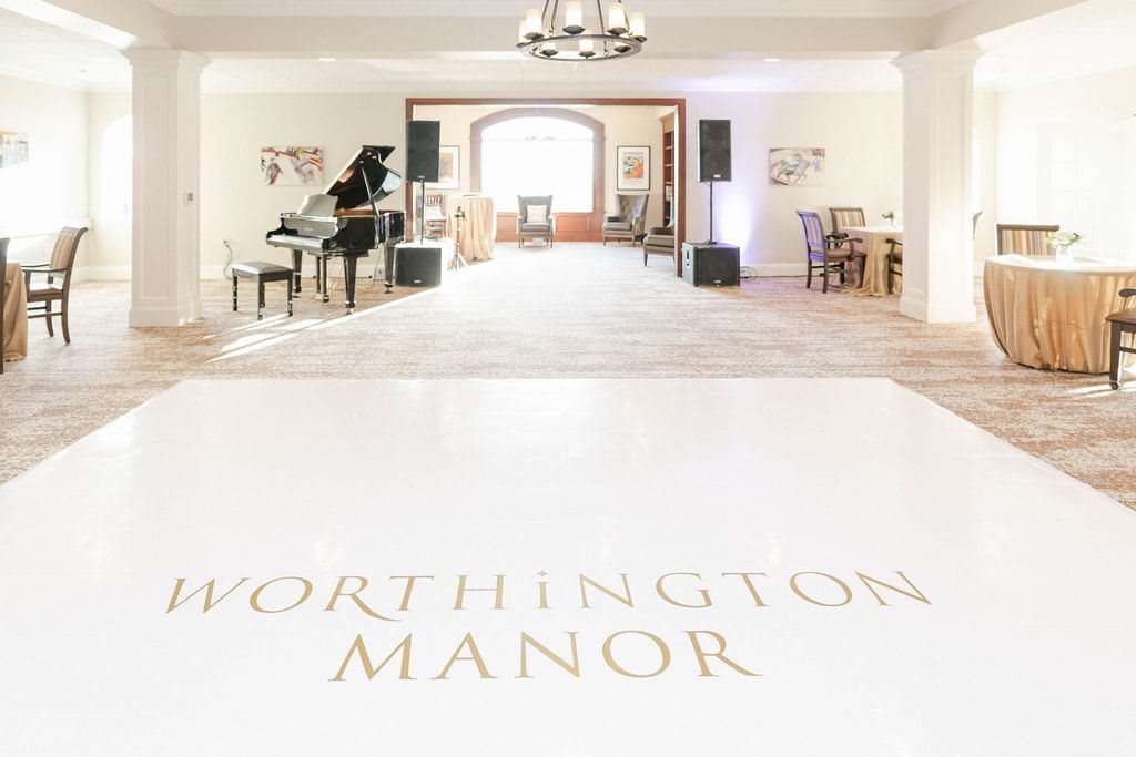 An elegant event space at Worthington Manor, featuring a piano and chandelier.