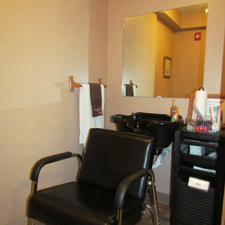 An interior view of a hair salon with a chair, mirror, and sink setup.