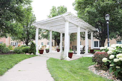 A serene outdoor space featuring a white pergola surrounded by lush greenery and a winding pathway.
