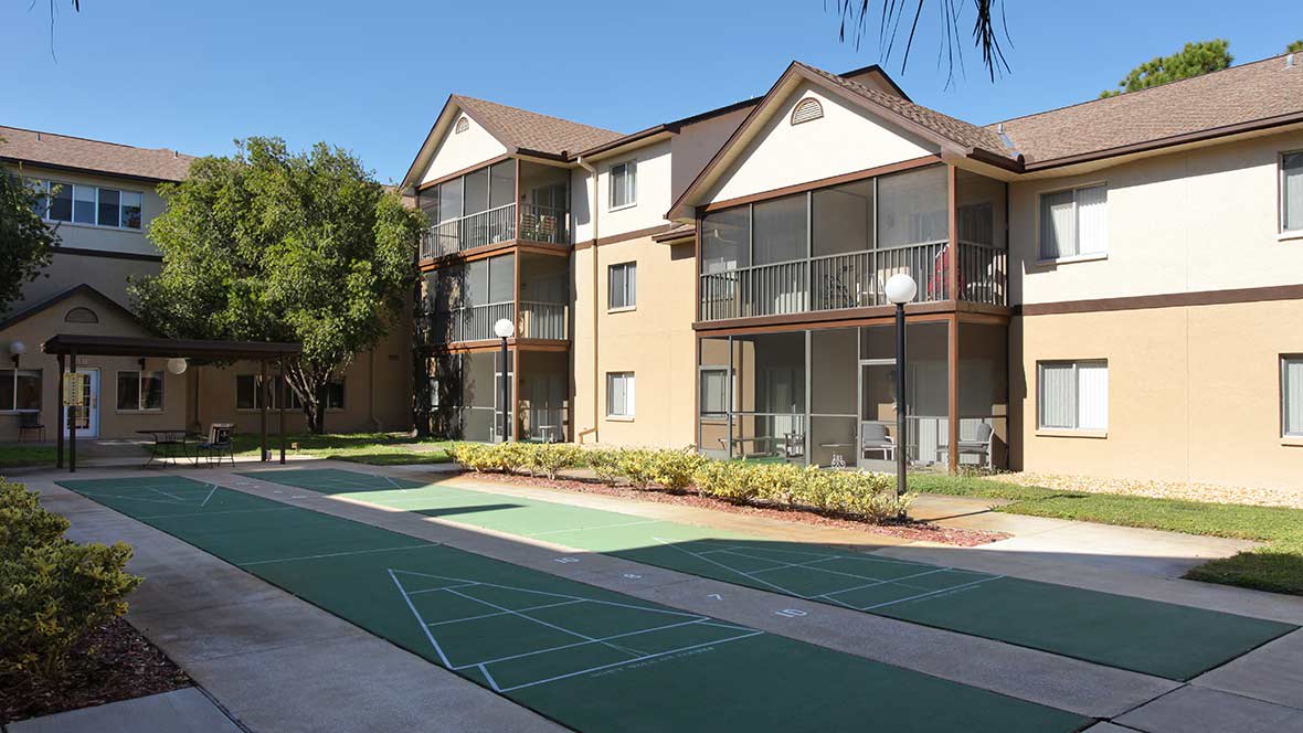 A residential apartment building with outdoor courts and clear skies.