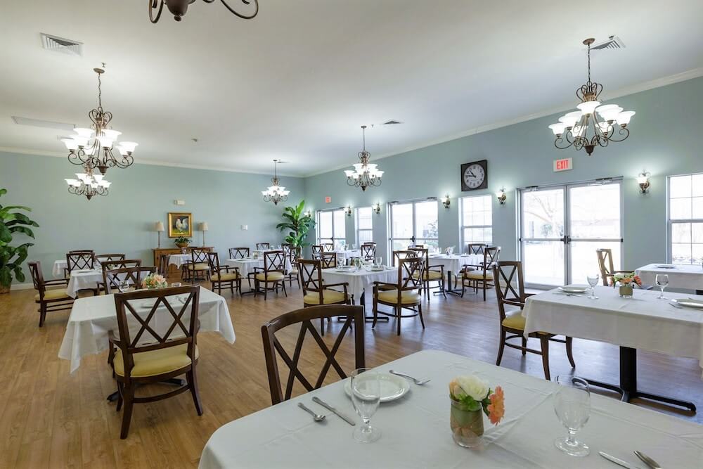 A well-lit dining room with elegantly set tables and chairs, featuring stylish decor and ambient lighting.