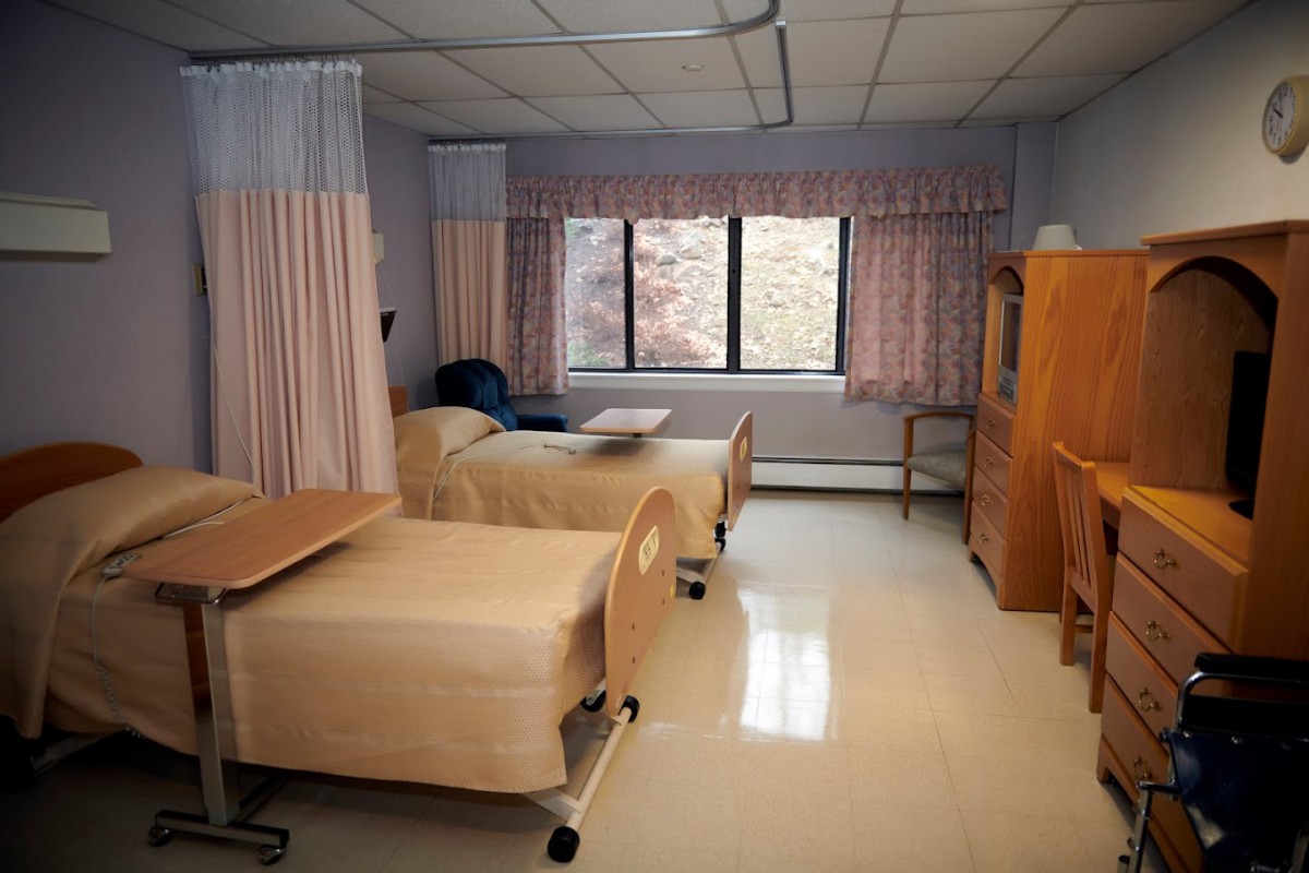 A hospital room with two beds and a large window.