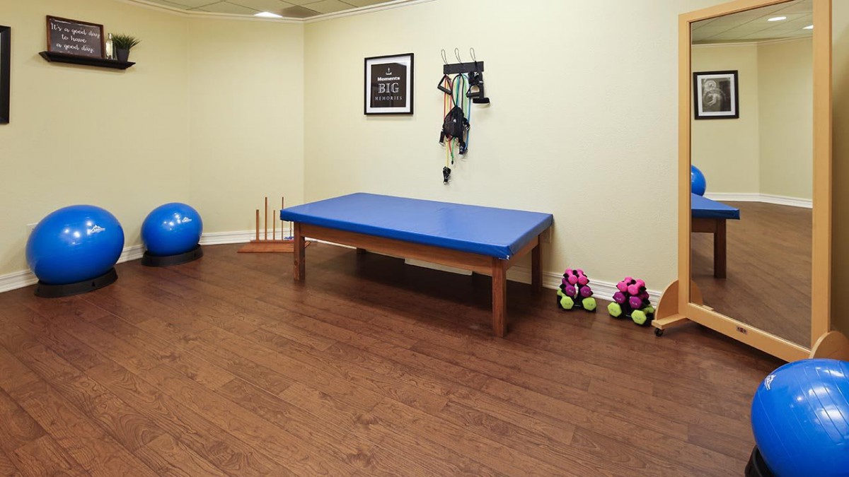 A well-equipped exercise room with a therapy table and various fitness gear.