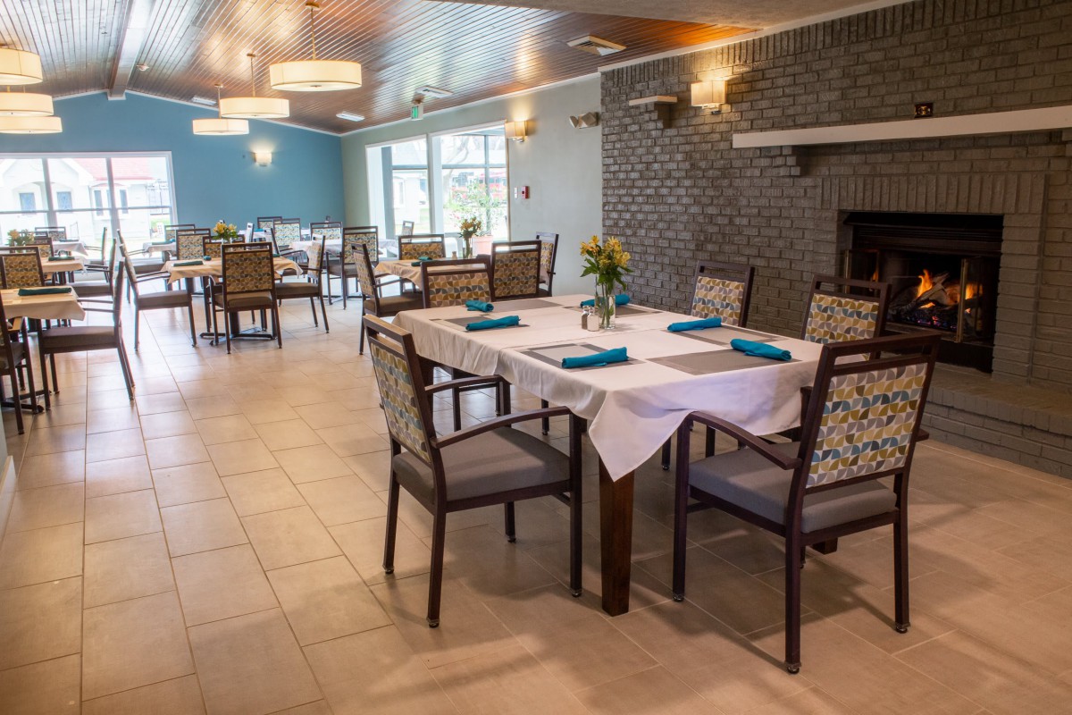 A well-decorated dining area with neatly arranged tables and chairs, featuring elegant lighting fixtures.