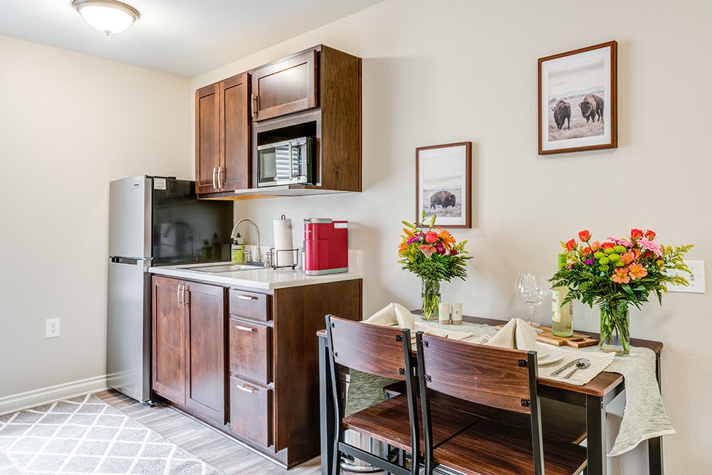 A cozy kitchen and dining area with modern appliances and a set table adorned with flowers.