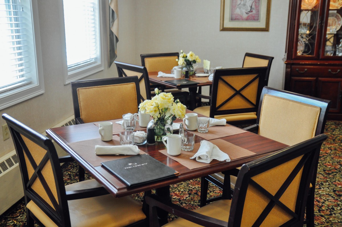 An elegantly set dining table with coffee cups and flowers in a restaurant setting.