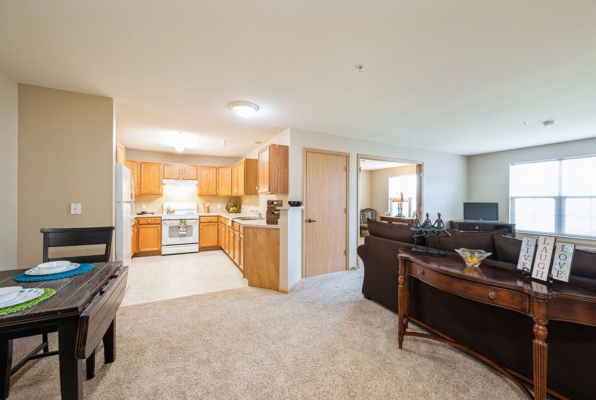 An open-layout living room and kitchen area with wooden cabinetry and comfortable furnishings.
