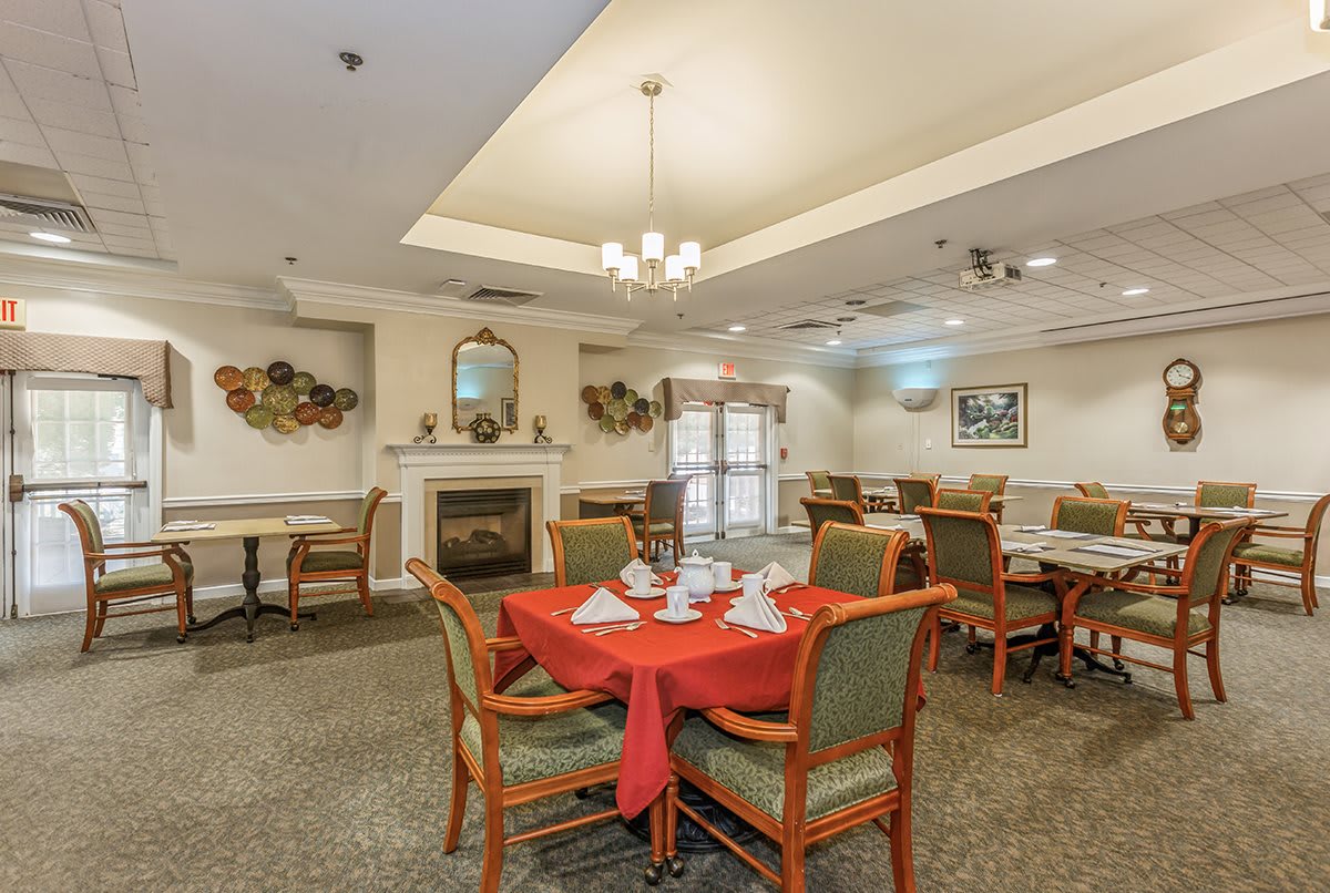 A well-decorated dining room with neatly arranged tables and a cozy fireplace.