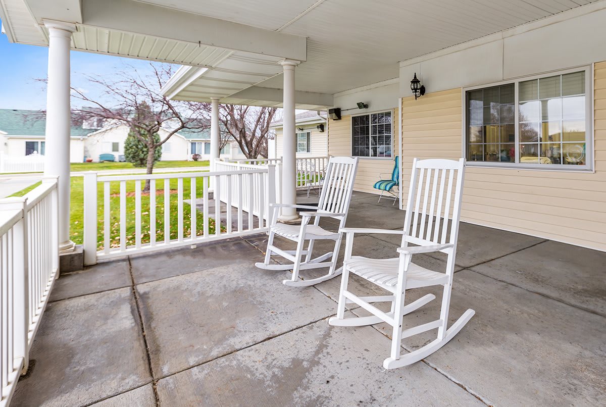 A cozy porch with two white rocking chairs, providing a tranquil outdoor space.