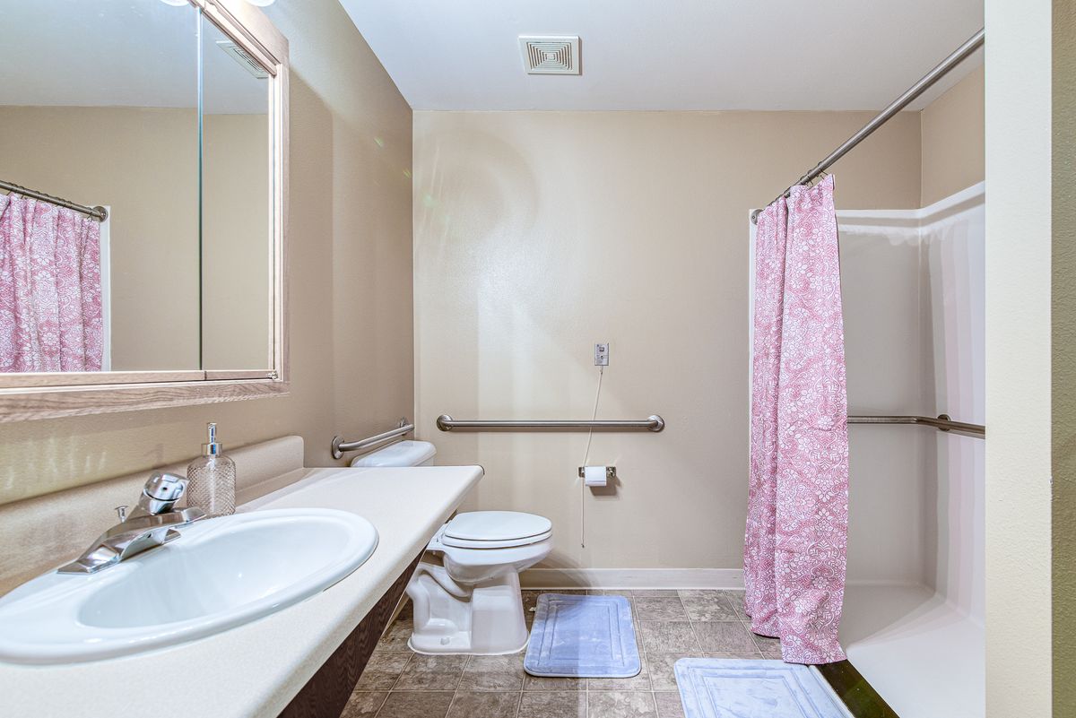 A clean and tidy bathroom with a pink shower curtain and matching floor mat.