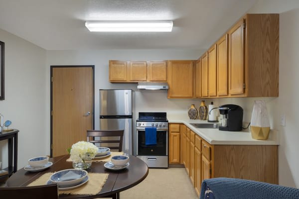 A modern kitchen with wooden cabinets, stainless steel appliances, and a dining table set for a meal.