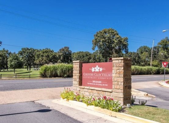 Entrance sign to a scenic area with trees and landscaping.