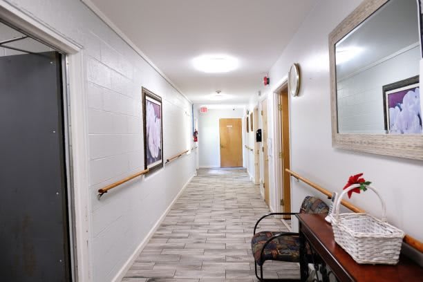 A clean and well-lit hallway in a healthcare facility with artwork on the walls and handrails for support.