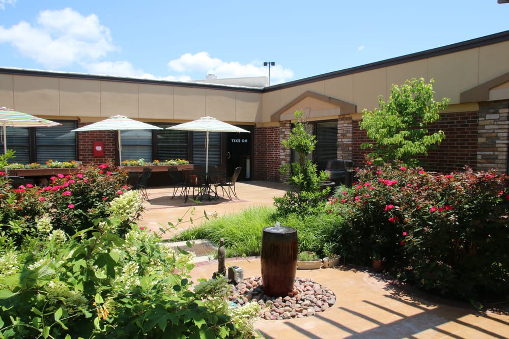 A well-landscaped courtyard featuring outdoor seating with umbrellas on a sunny day.