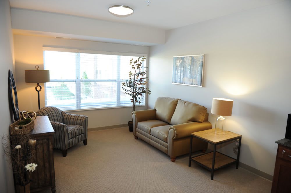 A cozy living room with a sofa, armchair, and soft lighting.