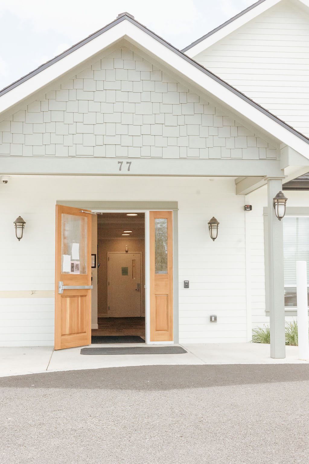 A welcoming entrance to a building with open wooden doors and exterior lights.