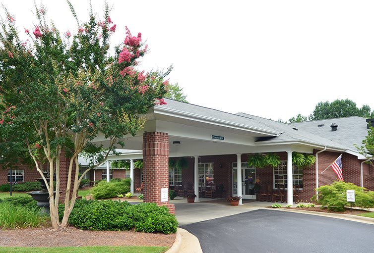 An entrance with a covered walkway surrounded by trees and landscaping.