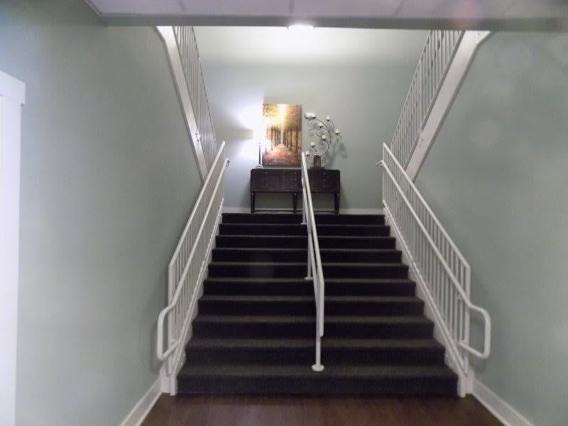 A staircase with a decorative table at the top, featuring a painting and a plant.