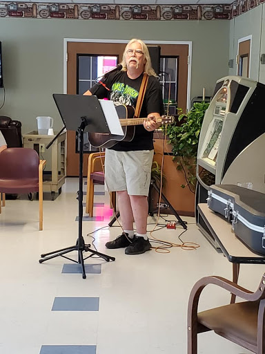 A musician performing with an acoustic guitar in a communal space.
