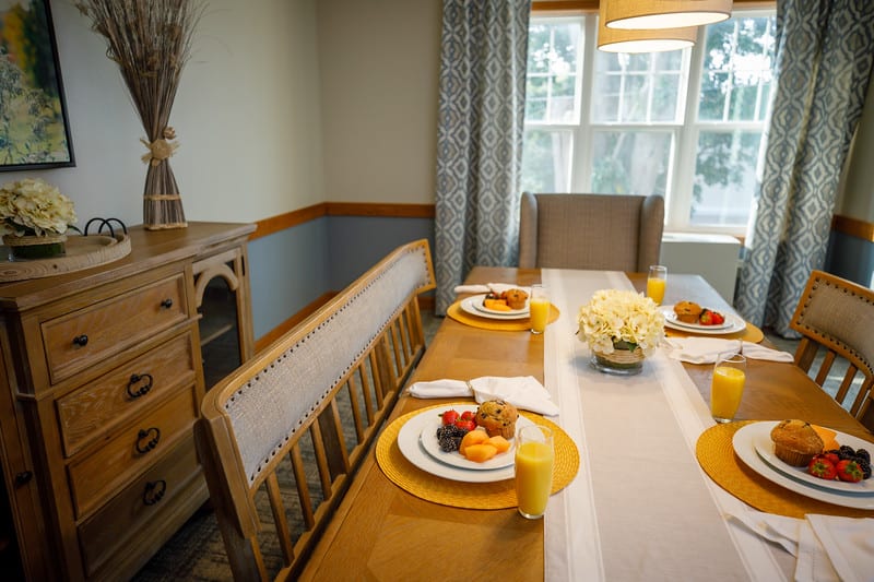 A cozy dining room table set for breakfast with fruit and juice.