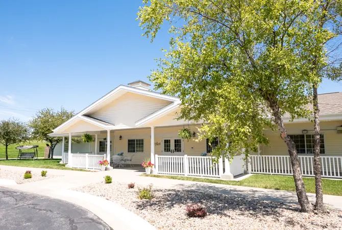 A charming residential house with a spacious porch and surrounding greenery.