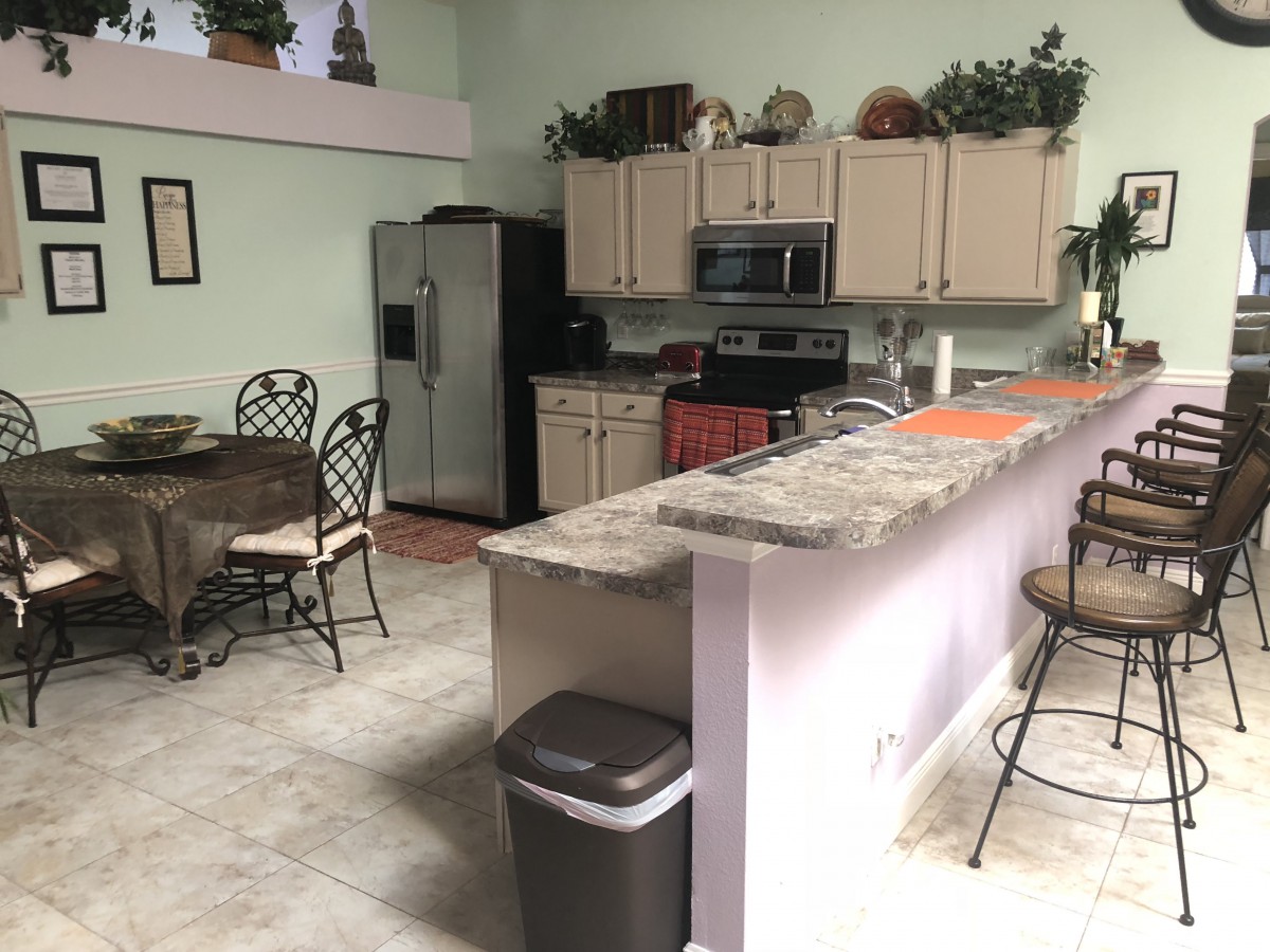 A modern kitchen with dining area featuring a refrigerator, stove, and countertop seating.