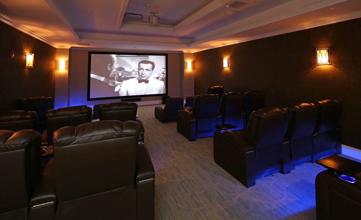 A luxurious home theater room with comfortable recliner seating and a large projection screen.