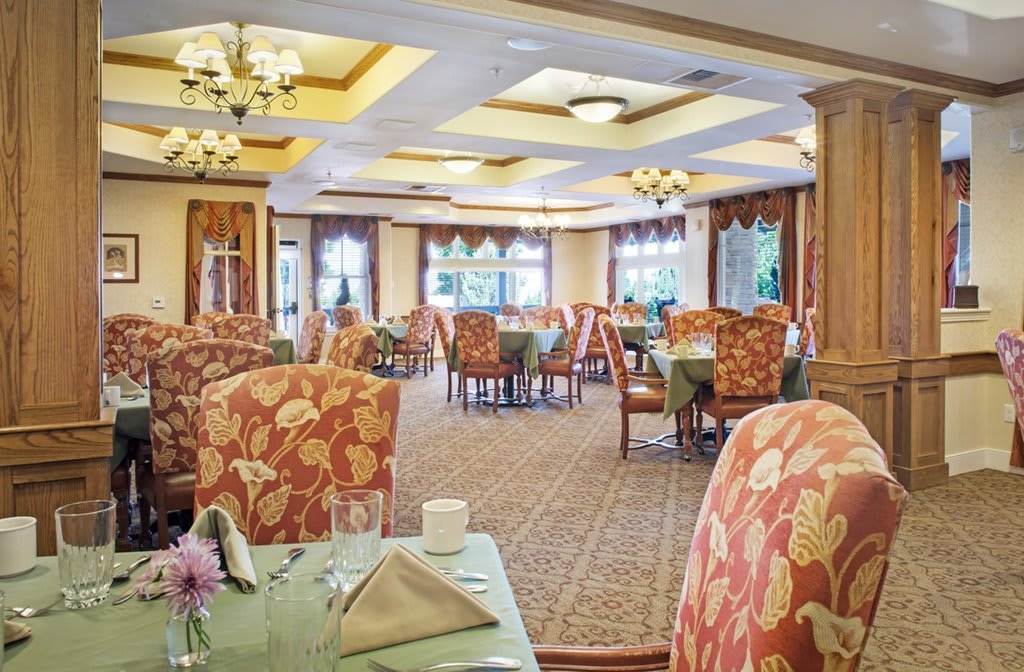 A beautifully decorated dining area with elegantly set tables and floral-patterned chairs.