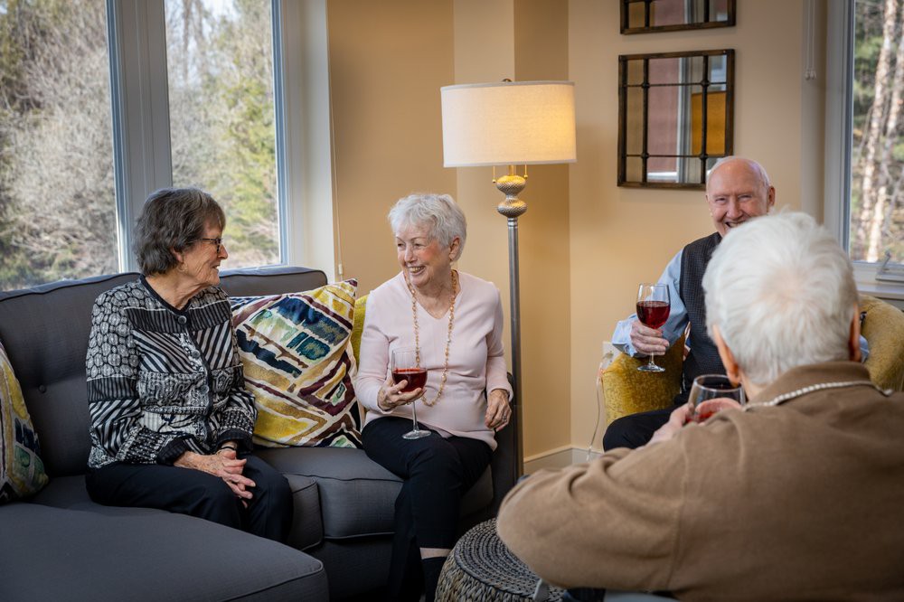 A group of seniors enjoying a conversation and drinks in a cozy living room setting.