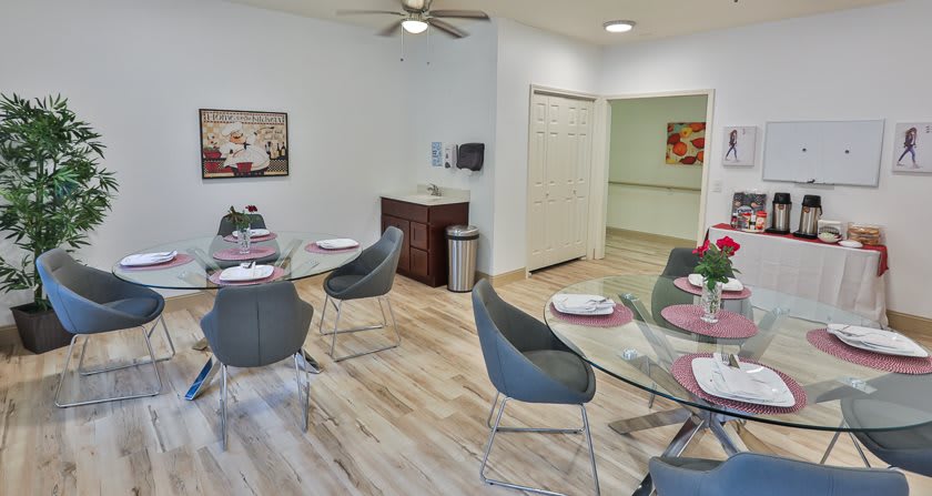A modern dining area with stylish chairs and neatly set tables on a wooden floor.