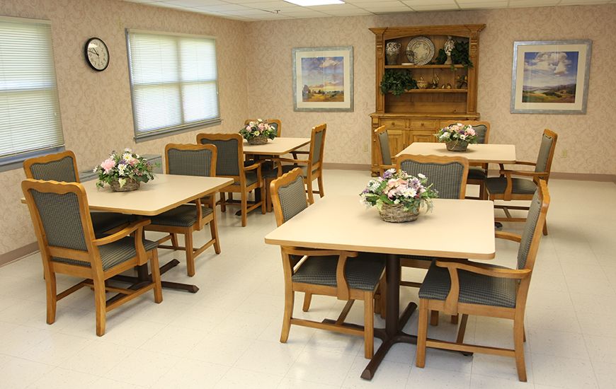 A neatly arranged dining room with tables and chairs, decorated with floral centerpieces.