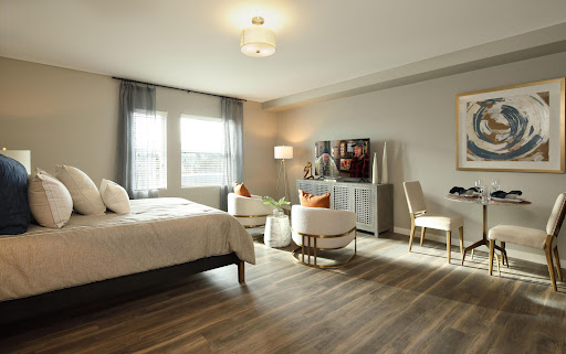 A beautifully designed modern bedroom featuring a cozy bed, stylish seating area, and ample natural light.