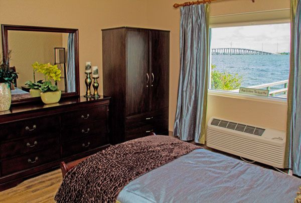 A cozy bedroom with dark wood furniture and a scenic coastal view from the window.
