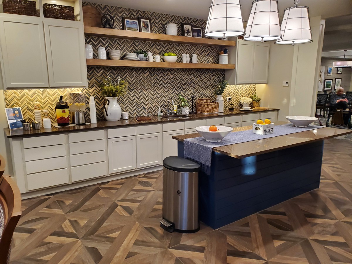 A modern kitchen with an island, stylish lighting, and open shelving.