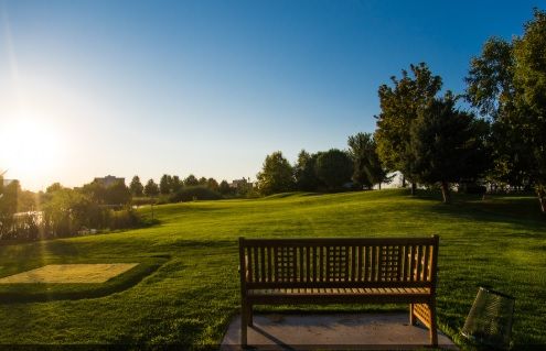 A peaceful golf course landscape with a wooden bench overlooking the green at sunset.