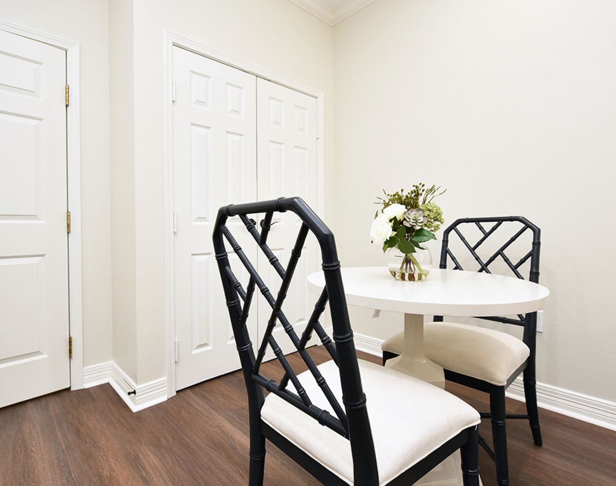 A minimalist dining area with elegant chairs and a round table, accented by a small floral arrangement.