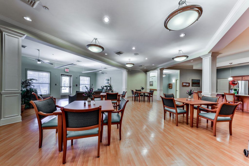 A spacious dining area with multiple tables and chairs, featuring hardwood flooring and contemporary lighting fixtures.