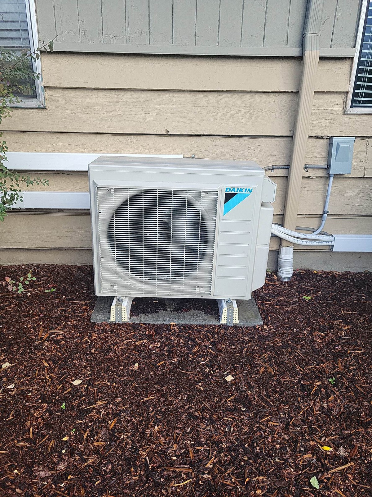 An outdoor air conditioning unit mounted against an exterior wall.