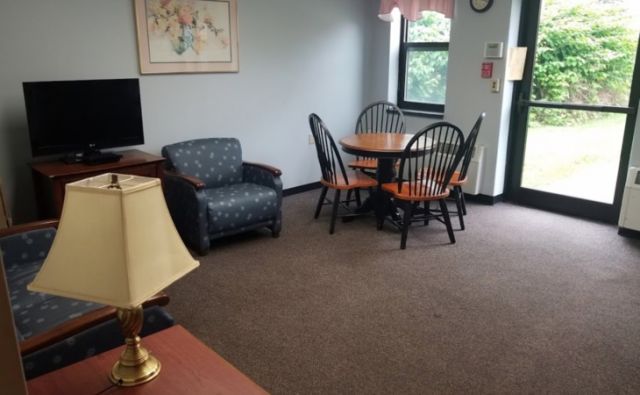 A cozy living room with a dining table and chairs next to an armchair.