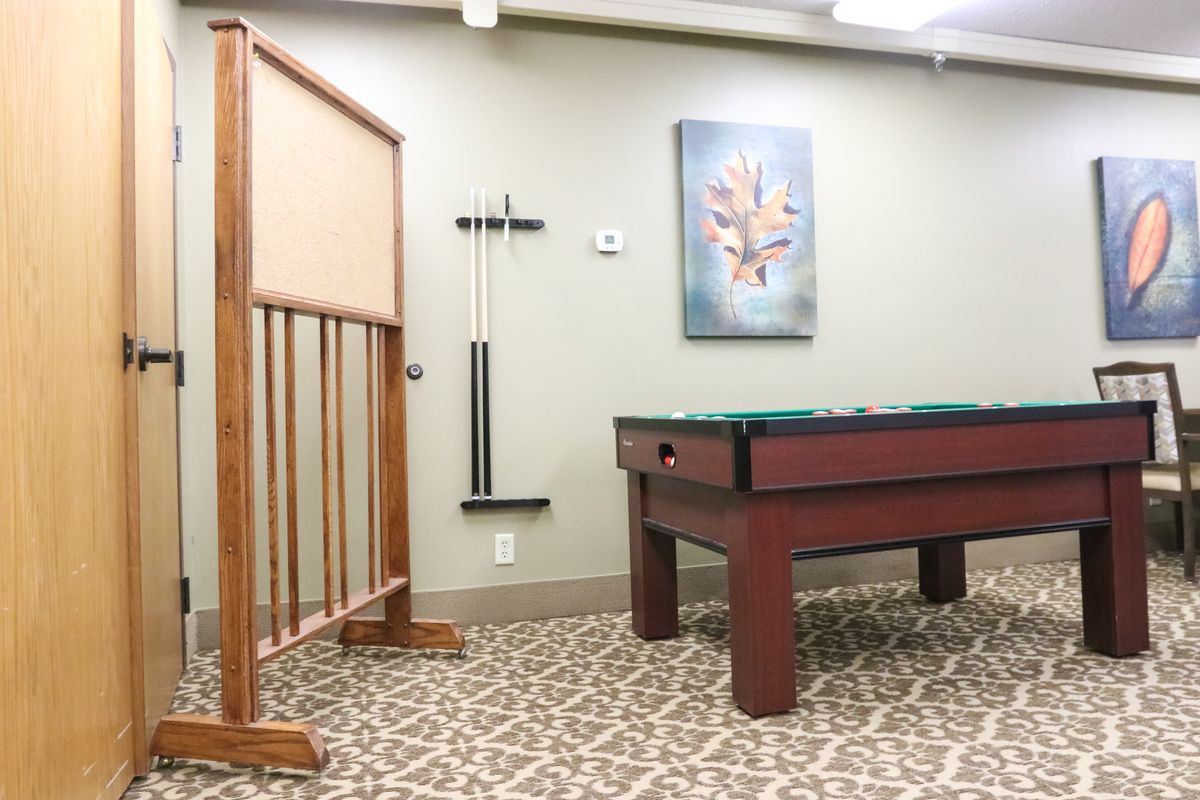 A game room with a pool table and cue sticks mounted on the wall.