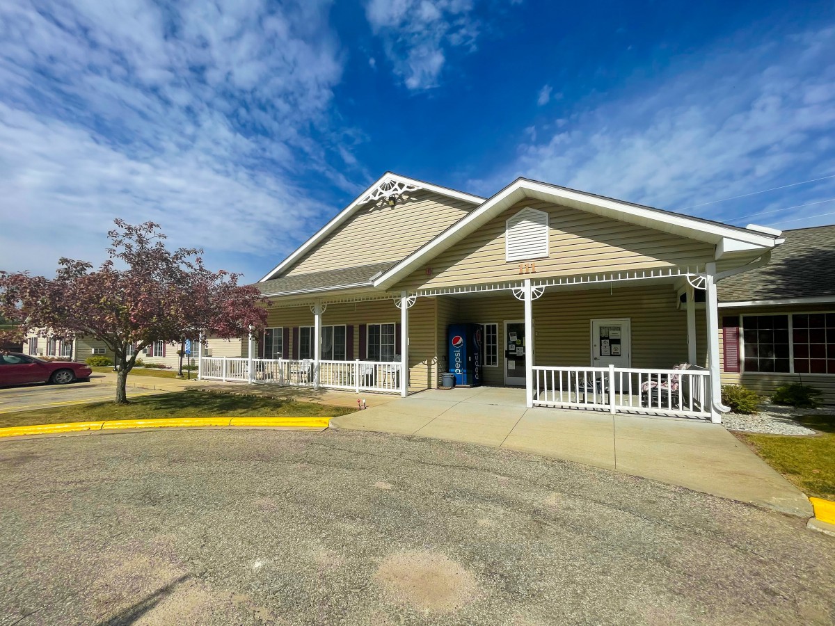 A quaint, single-story building with a porch under a partly cloudy sky.