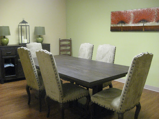 A modern dining room featuring a dark wooden table surrounded by elegant chairs, complemented by green walls and decorative artwork.
