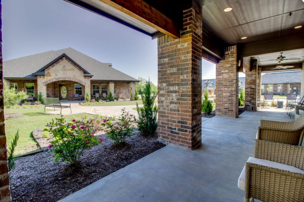 A view from the porch of a brick house overlooking a landscaped garden area.