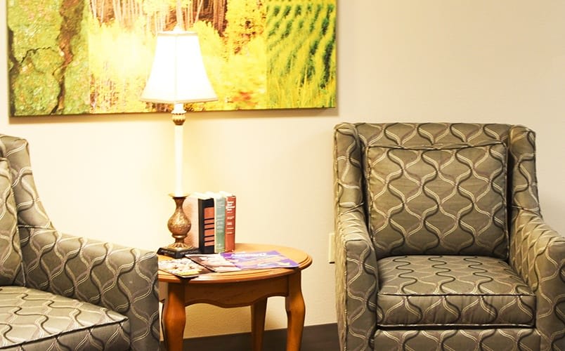 A cozy living room corner with a patterned armchair, side table, and lamp.