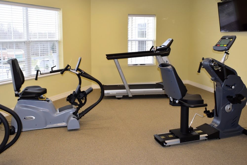 A small gym with various exercise machines, including a treadmill and stationary bikes.